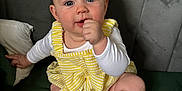Willow joined the competition — help win amazing prizes! baby, child, infant, yellow_outfit, yellow_socks, sitting, thumb_in_mouth, blue_eyes, curious_expression, green_surface, gray_background, indoor, cute, portrait, person, clothing, soft_lighting, close_up, face, head