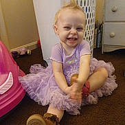 Ivy is registered to the contest to win money with this photo: brown_boots, carpet, casual, child, clapping, dresser, floor, furniture, hair_spike, happy, indoor, laundry_basket, playful, purple_tutu, room, sitting, smiling, toddler, toys, young_child