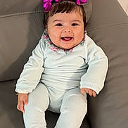 Sinaï a rejoint le concours — aidez-le/la à gagner de superbes lots ! baby, child, smiling, happy, pigtails, hair_bows, purple_bows, onesie, clothing, sitting, couch, leather, indoor, portrait, cute, infant, person, face, expression, comfort