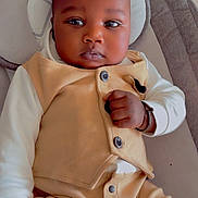 Mouhamed a rejoint le concours — aidez-le/la à gagner de superbes lots ! baby, infant, child, face, clothing, onesie, vest, hand, fist, seated, indoor, cushion, headrest, skin, portrait, cute, young, sleepy, expression, adorable