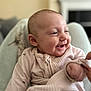 baby, smiling, laughing, infant, pajamas, hand, cozy, blurred_background, closeup, cute, child, person, indoor, soft_light, happy, skin, face, newborn, portrait, comfort