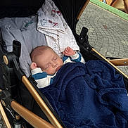 Enéo participe au concours pour gagner de l'argent avec cette photo : baby, sleeping, stroller, blanket, blue_blanket, baby_clothing, infant, peaceful, urban_background, pavement, advertisement, outdoor, child, face, head, hands, cozy, resting, toddler, cute