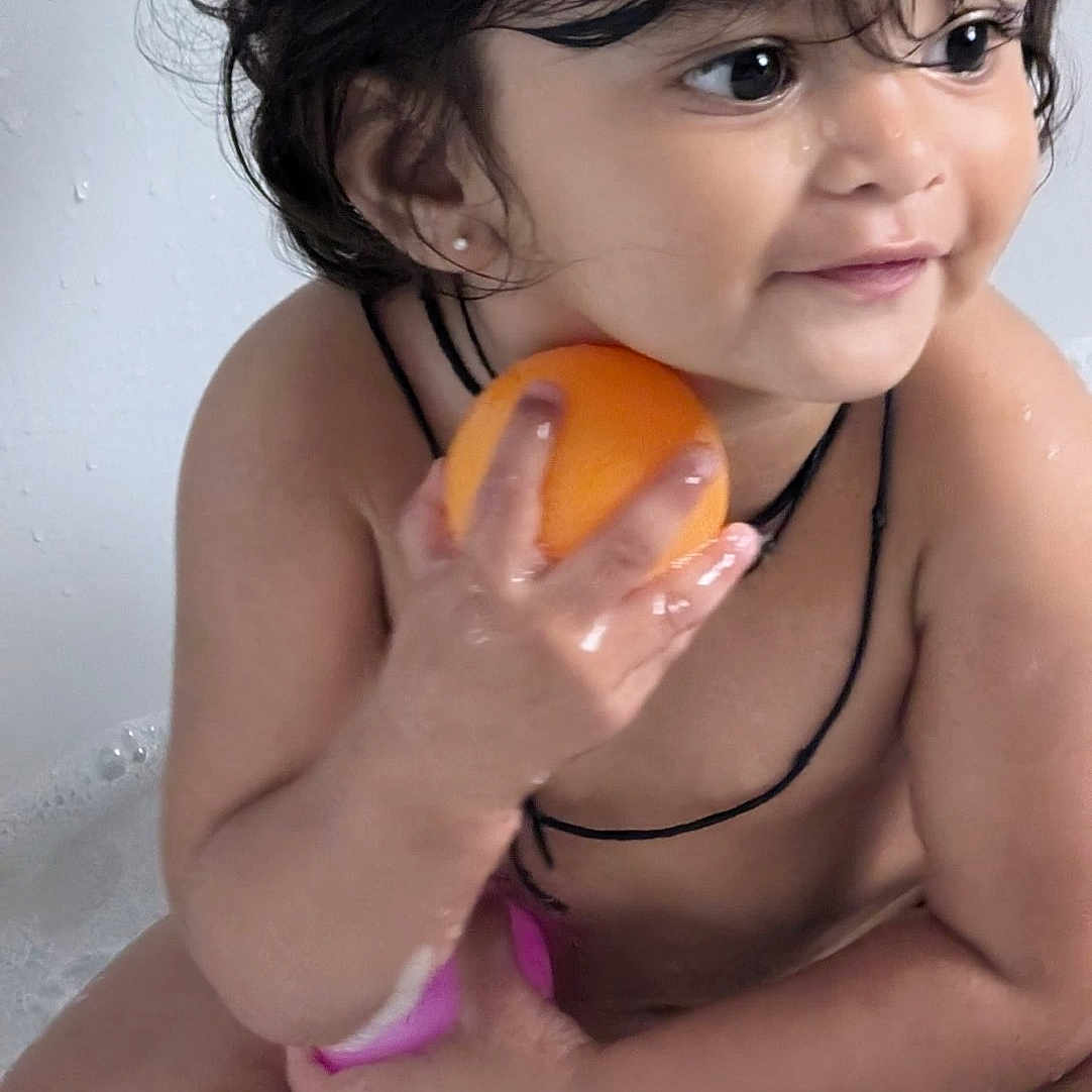 Aarvi is registered to the contest to win money with this photo: bath_time, bathtub, black_string, bubbles, child, cute, earrings, happy, indoor, orange, person, play, sitting, skin, smiling, toddler, toy, water, wet_hair, young_child