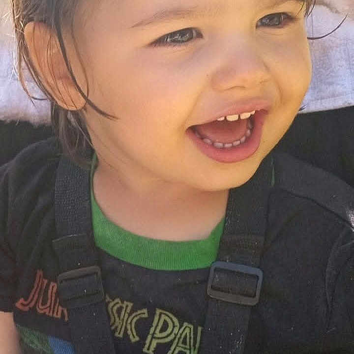 Jason is registered to the contest to win money with this photo: child, toddler, smiling, happy, laughing, portrait, face, eyes, hair, seated, car_seat, safety_harness, blanket, shirt, clothing, indoor, close_up, photograph, screenshot, joy