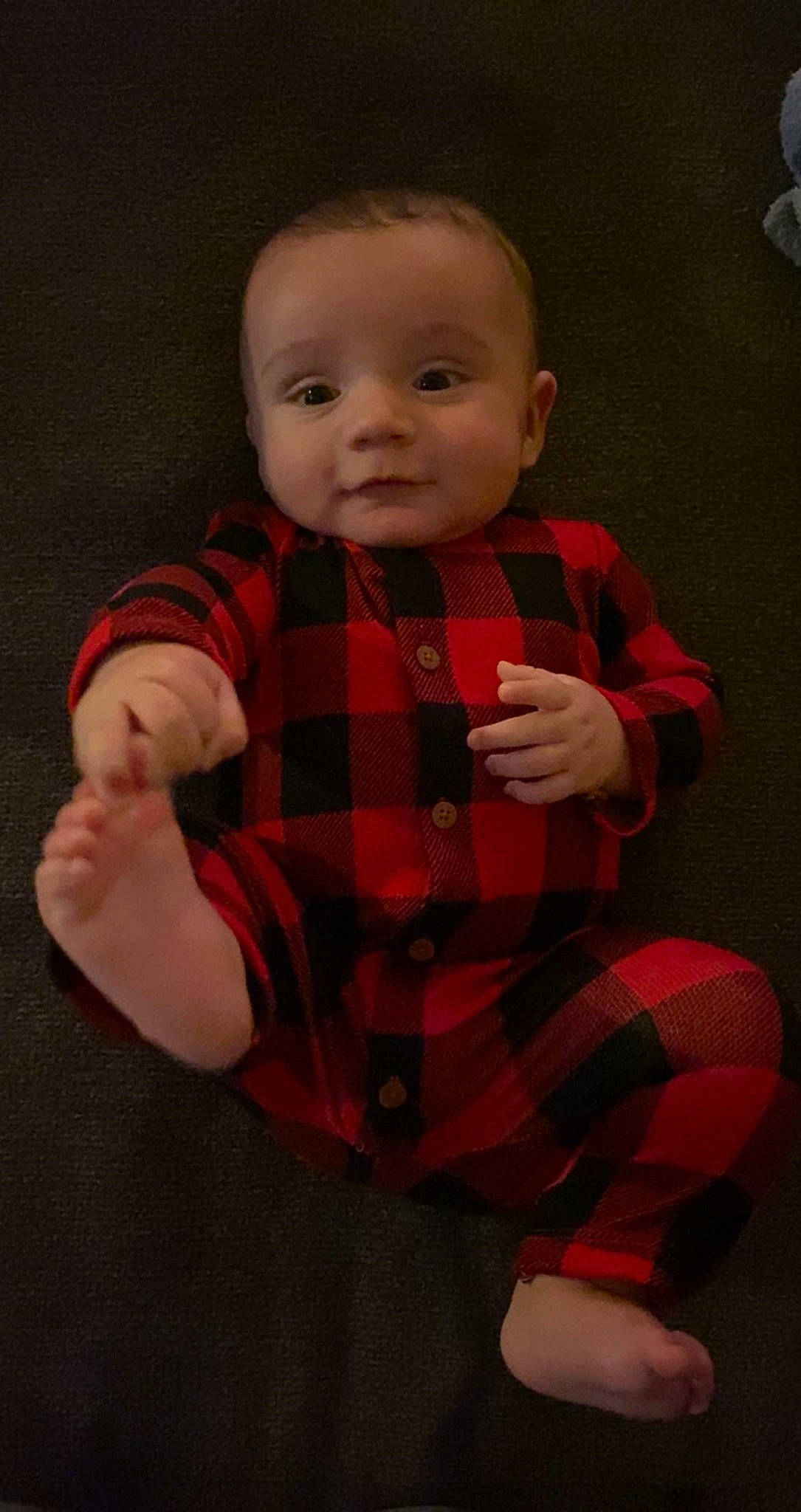 Beckham is registered to the contest to win money with this photo: arm, baby, baby_toddler_clothing, cheek, collar, eye, finger, gesture, hand, head, human_body, outerwear, pattern, person, plaid, skin, sleeve, standing, tartan, textile
