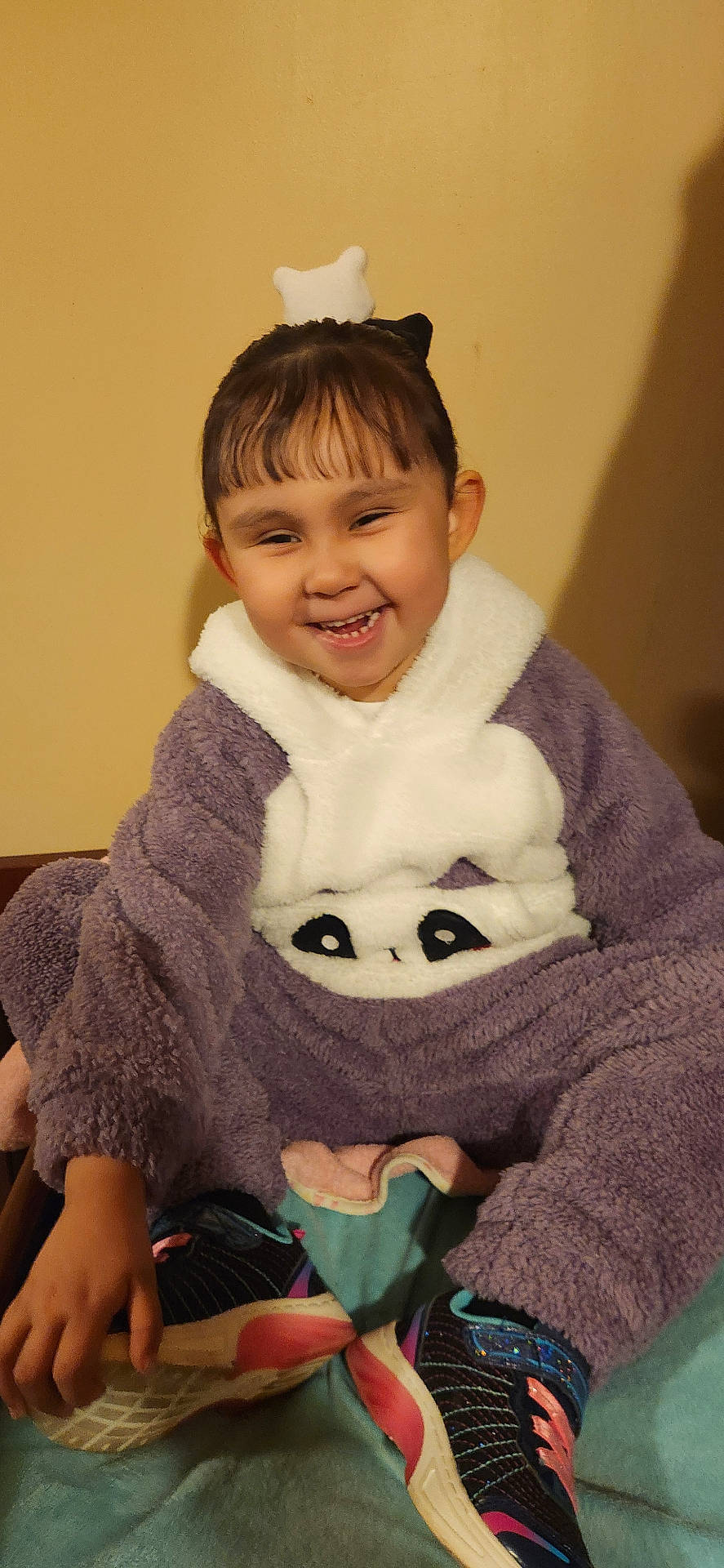 Emma is registered to the contest to win money with this photo: casual, child, cozy, cute, feet, funny_expression, happy, headband, indoor, long_sleeves, panda_outfit, portrait, purple_clothing, sitting, smiling, sneakers, toddler, toy, warm_clothing, young
