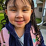 Emma is registered to the contest to win money with this photo: backpack, casual_clothing, child, closeup, curly_hair, cute, daylight, face, girl, greenery, happy, head, house, jacket, nature, outdoor, person, portrait, smiling, young