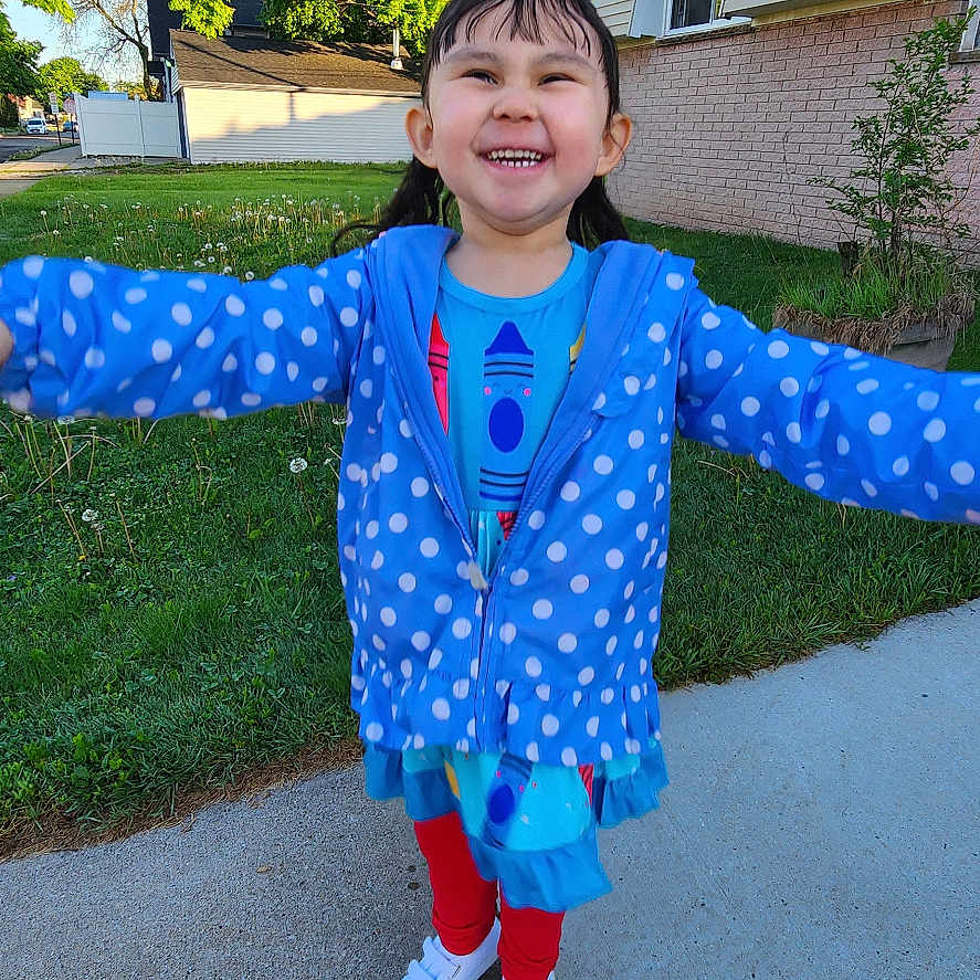 Emma is registered to the contest to win money with this photo: child, daylight, dress, girl, grass, happy, house, jacket, nature, outdoor, person, pigtails, polka_dot, portrait, red_leggings, sidewalk, smiling, suburban, trees, white_shoes