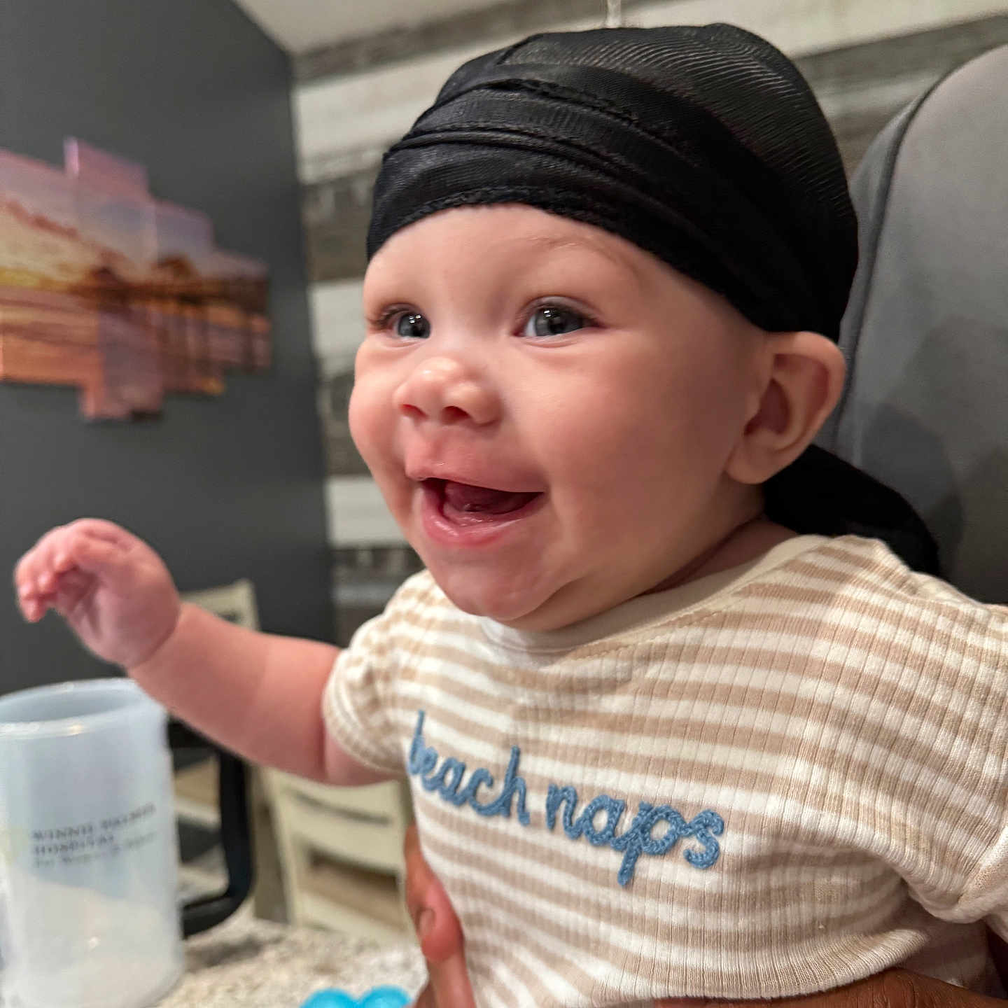 Kaeson joined the competition — help win amazing prizes! baby, background, child, clothing, cup, cute, expression, face, hands, happy, headwear, holding, indoor, infant, person, portrait, smiling, striped_shirt, table, toy