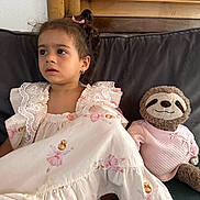 Marta joined the competition — help win amazing prizes! child, toddler, dress, ballerina_print, pink_bow, earrings, stuffed_animal, sloth, pink_sweater, couch, wooden_frame, curly_hair, indoor, portrait, sitting, cute, soft_toys, home, young_child, clothing