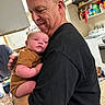 Maui is registered to the contest to win money with this photo: appliances, baby, black_shirt, brown_clothing, dog, family, father, holding, home, indoor, infant, kitchen, man, parent, pet, portrait, smiling, tender_moment, 抱?, 抱抱