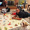 Maui is registered to the contest to win money with this photo: adult, baby, brick_wall, candid, carpet, dog, family, father, fireplace, furniture, home, indoor, infant, living_room, lying_down, pet, play_mat, portrait, smiling, toy