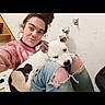 Lil P is registered to the contest to win money with this photo: person, dog, indoor, casual_clothing, jeans, ripped_jeans, white_dog, black_spots, staircase, wall, hairstyle, messy_bun, sitting, relaxed, pet, companion, portrait, smile, home, cozy
