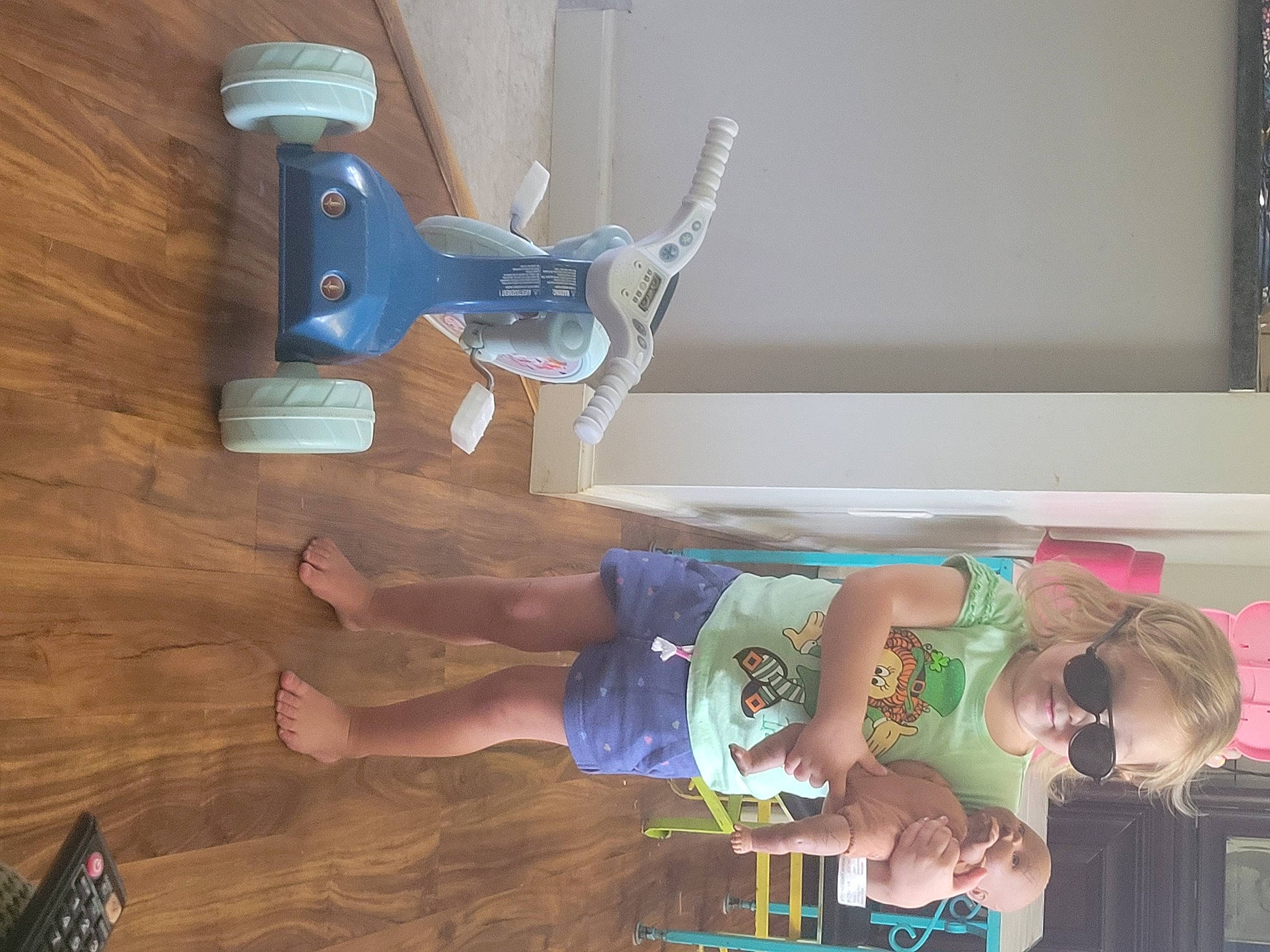 Ivey is registered to the contest to win money with this photo: balance, child, elbow, flooring, foot, fun, hardwood, hat, human_leg, knee, paint, person, room, shorts, snapshot, t_shirt, thigh, toddler, wood, wood_stain
