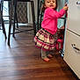 barefoot, cabinet, chair, child, curtain, expression, flooring, furniture, hair_clip, holding, home, indoor, kitchen, person, pink_sweater, plaid_skirt, standing, toddler, wooden_floor, young_child