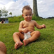 Lalu is registered to the contest to win money with this photo: baby, barefoot, beach, chair, child, clouds, curly_hair, diaper, grass, grass_blade, infant, nature, outdoors, palm_tree, portrait, sitting, sky, smiling, sunlight, tropical