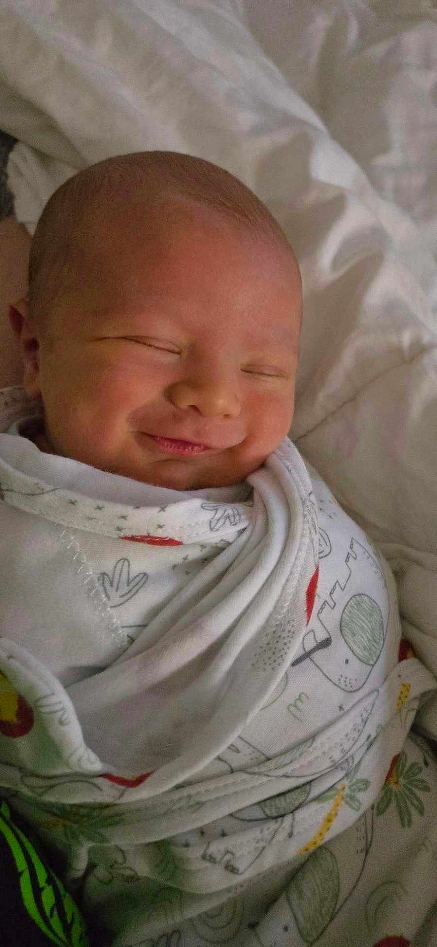 Baylor is registered to the contest to win money with this photo: baby, newborn, smile, sleeping, blanket, bed, cozy, infant, wrapped, cute, face, peaceful, soft, child, portrait, clothing, resting, sleep, closeup, indoors