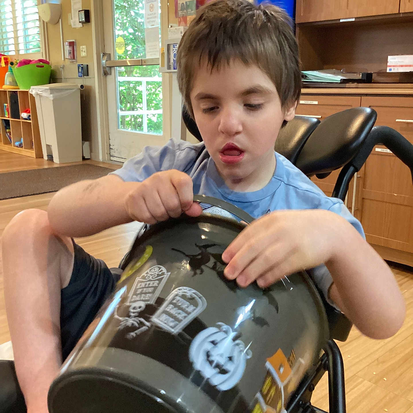 Raven joined the competition — help win amazing prizes! blue_shirt, boy, bucket, cabinet, child, curtains, decorations, door, furniture, halloween, indoor, light, person, plastic_bucket, pumpkin, shorts, tombstone, wheelchair, window, wooden_floor