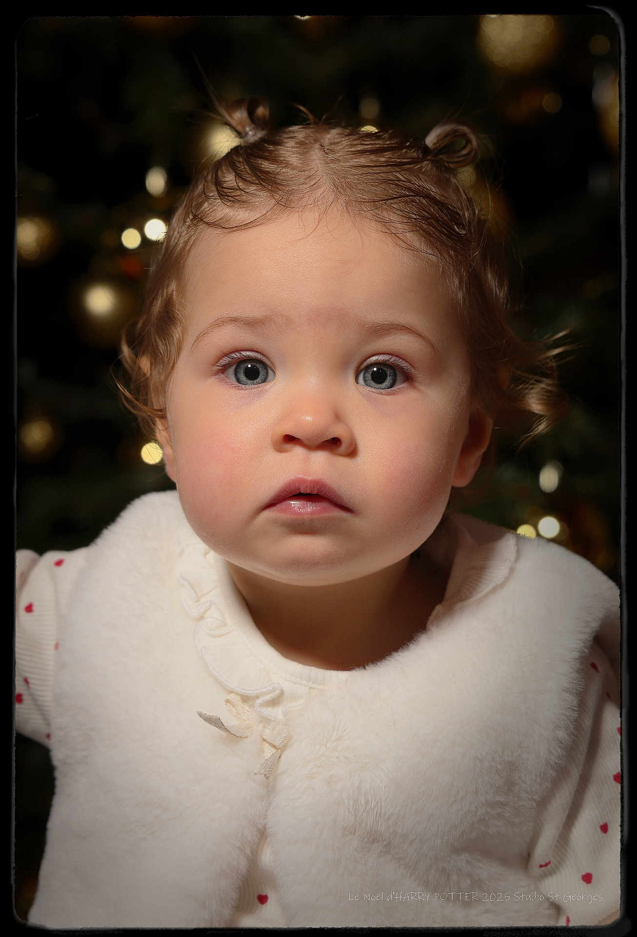 Kiara a rejoint le concours — aidez-le/la à gagner de superbes lots ! toddler, child, portrait, baby, face, eyes, hair, curly_hair, white_vest, soft_lighting, indoor, holiday_lights, background_bokeh, cute, innocent, expression, close_up, winter_clothing, studio_photo, warm_tones