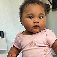 Amalïa a rejoint le concours — aidez-le/la à gagner de superbes lots ! baby, child, infant, pink_clothing, floral_pattern, cute, curious, face, portrait, indoor, person, young_child, chubby_cheeks, short_hair, onesie, skin, hand, expression, room, background