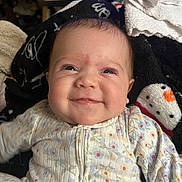 Journey is registered to the contest to win money with this photo: apparel, baby, blanket, child, closeup, cozy, cute, expression, face, floral_pattern, happy, indoors, infant, onesie, person, portrait, smile, snowman, warm, young