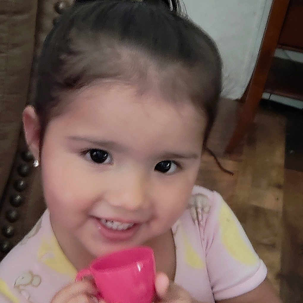 Layla joined the competition — help win amazing prizes! bodypart, child, clothing, couch, cup, electronics, face, female, finger, furniture, girl, hand, happy, head, person, phone, photography, portrait, smile, t_shirt