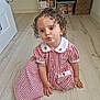 child, toddler, curly_hair, dress, red_and_white, checkered, floor, wooden_floor, indoor, pouting, cute, baby, person, sitting, hand, foot, room, storage, toy, curly_hair_toddler
