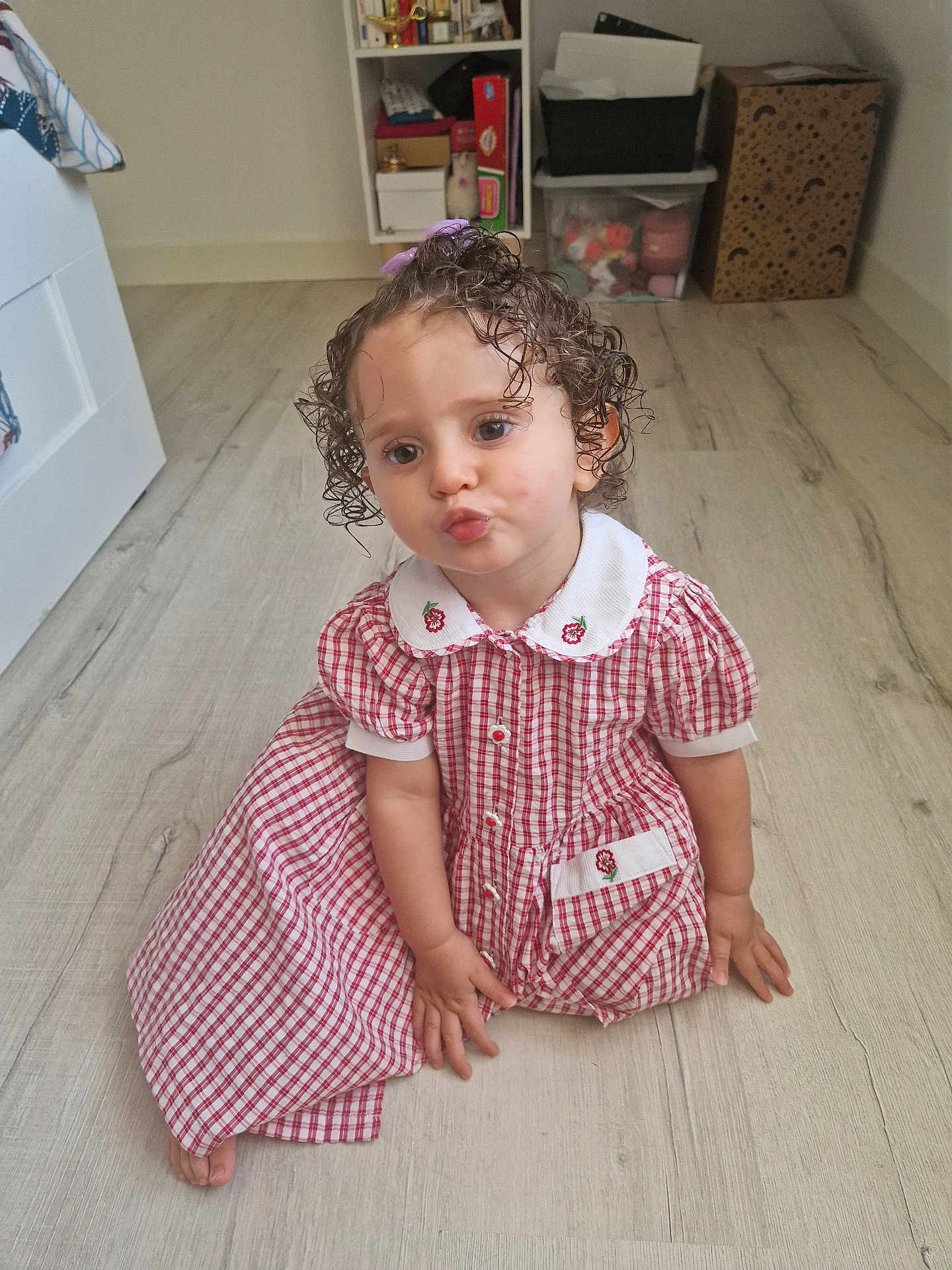 Eden a rejoint le concours — aidez-le/la à gagner de superbes lots ! child, toddler, curly_hair, dress, red_and_white, checkered, floor, wooden_floor, indoor, pouting, cute, baby, person, sitting, hand, foot, room, storage, toy, curly_hair_toddler