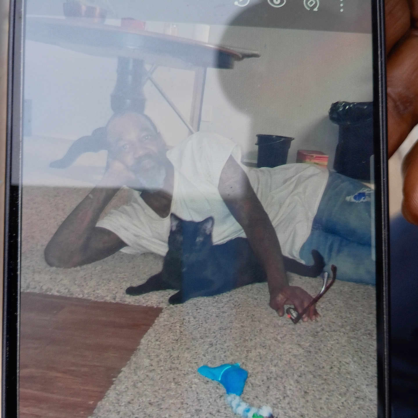Bg joined the competition — help win amazing prizes! man, black_cat, carpet, indoor, phone_screen, reflection, toy, glasses, table, casual_clothing, relaxed, home, floor, pet, hand, shadow, jeans, beard, tattoo, living_room
