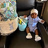 baby, child, chair, black_leather, gift_basket, easter, bucket, toy, clothing, hat, socks, smile, indoor, person, celebration, holiday, furniture, cute, comfort, accessory