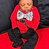 baby, infant, sleeping, red_clothing, black_clothing, mittens, hat, bow_tie, milestone, one_month, sitting, portrait, indoor, child, cute, young, peaceful, black_background, red_background, clothing