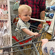 Elijah joined the competition — help win amazing prizes! toddler, shopping_cart, child, store, clothing, adult, hand, metal, floor, plaid_shirt, tattoo, baby, shopping, aisle, rack, sleeve, casual, footwear, cute, curious