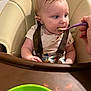 baby, high_chair, feeding, spoon, food, child, infant, meal, curious, beige, plastic_bowl, hand, table, clothing, straps, indoor, closeup, face, expression, messy