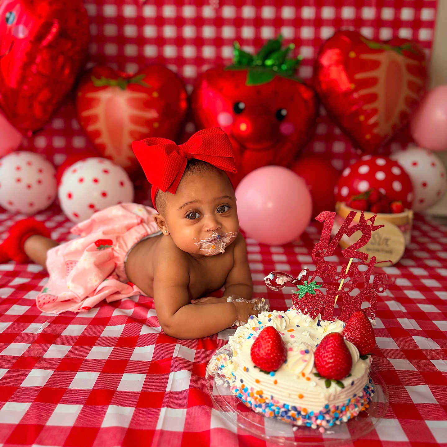 Azari is registered to the contest to win money with this photo: baby, child, cake, strawberry, balloon, red_bow, checkered_tablecloth, birthday, celebration, cream, sprinkles, decorations, cute, messy, smiling, face, hands, pink_balloon, heart_balloon, photography