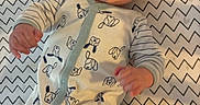 Thor is registered to the contest to win money with this photo: baby, infant, smile, onesie, dog_pattern, zigzag_pattern, blanket, happy, lying_down, cute, child, face, hand, clothing, baby_wipes, indoor, portrait, young_child, playful, bright_eyes