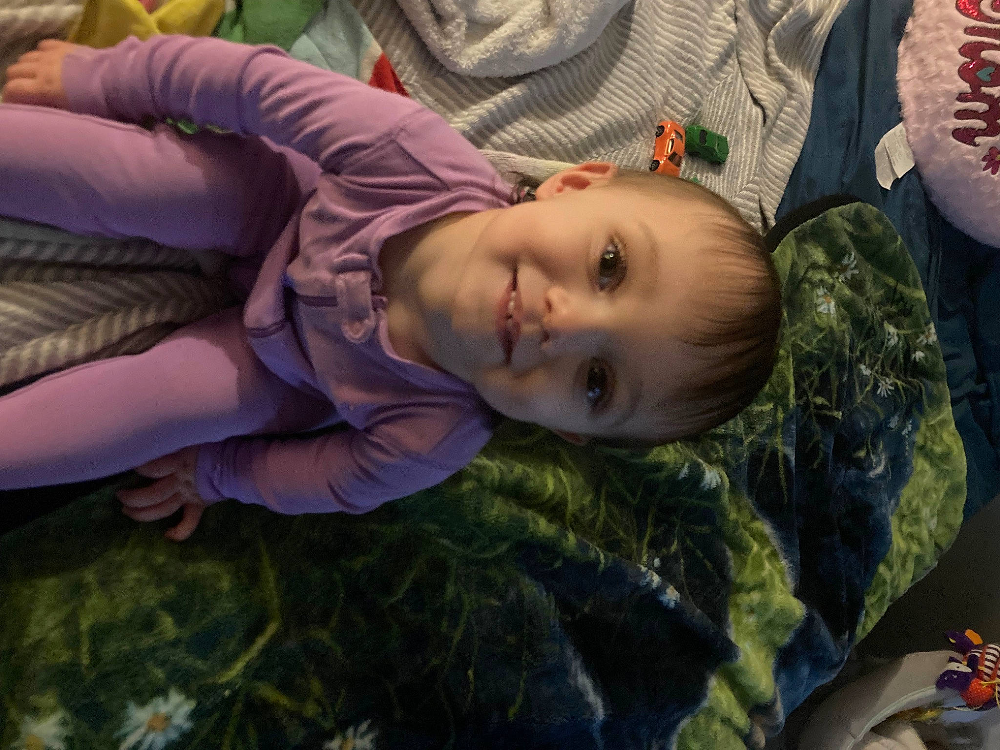 Gabriella is registered to the contest to win money with this photo: baby, cheek, child, comfort, eye, face, facial_expression, fun, grass, hairstyle, happy, head, iris, joy, military_camouflage, person, plant, sitting, smile, toddler