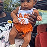 Ahla joined the competition — help win amazing prizes! baby, child, infant, headband, flower, orange_shorts, white_shirt, person, adult_hand, outdoor, car, car_interior, trees, house, blanket, glasses, serious_expression, clothing, holding, portrait