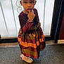 accessories, child, clothing, costume, door, dress, face, fashion, female, footwear, formalwear, girl, head, pants, person, photography, portrait, shoe, sitting, toy