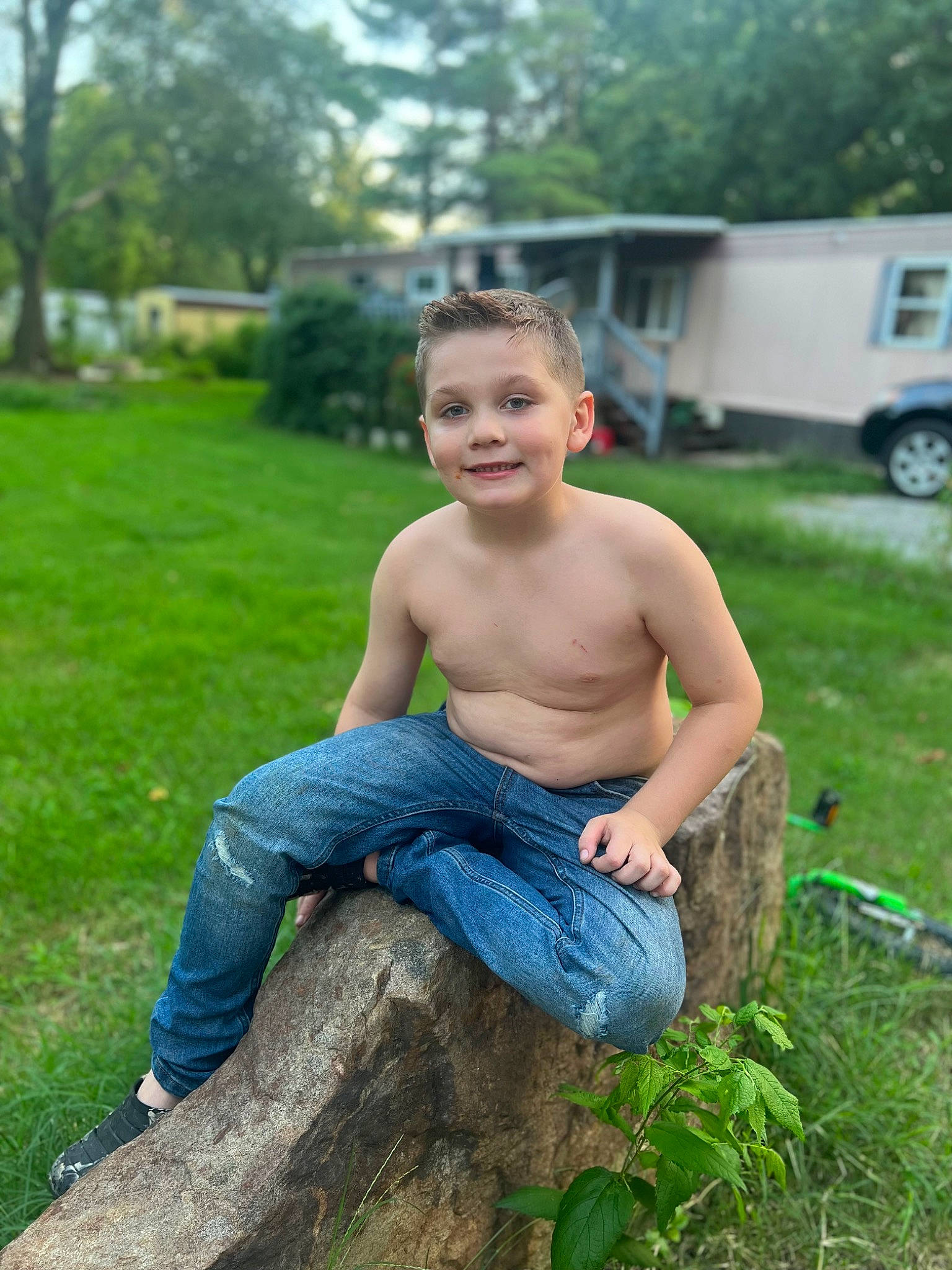 Camden is registered to the contest to win money with this photo: barechested, denim, electric_blue, flash_photography, fun, garden, grass, happy, human_leg, jeans, joy, leisure, people_in_nature, person, plant, sitting, smile, soil, thigh, tire