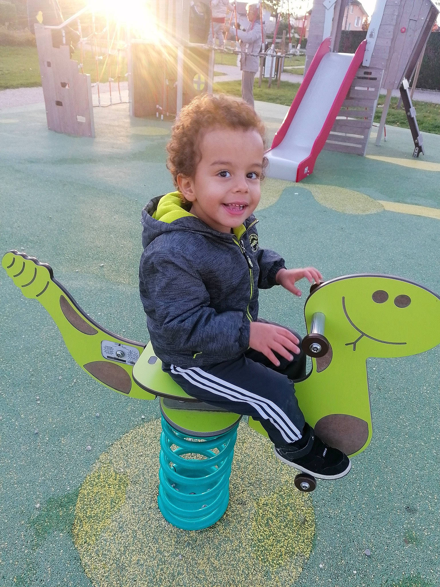 Zack participe au concours pour gagner de l'argent avec cette photo : asphalt, baby_toddler_clothing, child, city, fun, grass, green, happy, joy, leisure, outdoor_play_equipment, people_in_nature, person, play, playground, public_space, recreation, sitting, smile, t_shirt