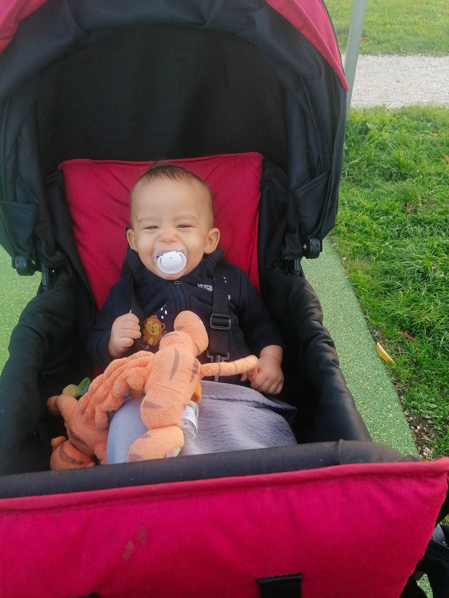 Zayan a rejoint le concours — aidez-le/la à gagner de superbes lots ! baby, baby_carriage, baby_products, baby_toddler_clothing, child, comfort, event, eye, fashion_accessory, fun, grass, human_body, lap, leisure, person, recreation, red, sitting, toddler, toy