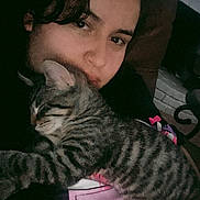 Patricio is registered to the contest to win money with this photo: person, cat, tabby_cat, sleeping, cuddling, indoor, cozy, closeup, face, pet, animal, striped, comfort, resting, casual, dark_background, human, love, affection, relaxation