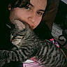 person, cat, tabby_cat, sleeping, cuddling, indoor, cozy, closeup, face, pet, animal, striped, comfort, resting, casual, dark_background, human, love, affection, relaxation