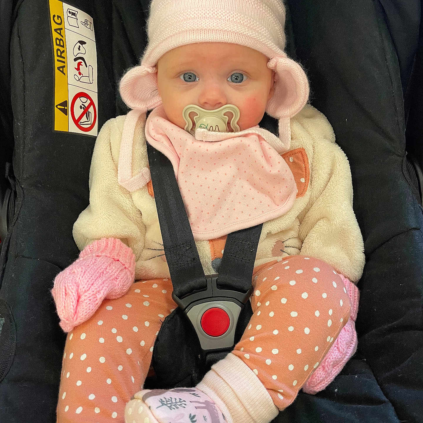 Nala is registered to the contest to win money with this photo: baby, bonnet, cap, car, car_interior, carseat, clothing, coat, face, hat, head, hosiery, pants, person, photography, portrait, sock, toy, transportation, vehicle