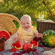 Rain joined the competition — help win amazing prizes! baby, child, smiling, watermelon, fruit, basket, picnic, blanket, outdoor, sunlight, greenery, happy, yellow_clothing, summer, nature, cute, sitting, food, fresh, playful