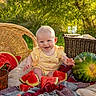baby, child, smiling, watermelon, fruit, basket, picnic, blanket, outdoor, sunlight, greenery, happy, yellow_clothing, summer, nature, cute, sitting, food, fresh, playful