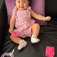 Elina participe au concours pour gagner de l'argent avec cette photo : baby, child, smiling, pink_dress, socks, toy, couch, pillow, black_leather, happy, sitting, cute, hair_bun, indoor, infant, play, bracelet, colorful, small_toy, relaxed