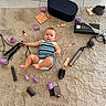 baby, child, infant, rug, hair_curlers, hair_styling_tools, flat_iron, makeup, lipstick, cosmetics, curly_hair_tools, plush_rug, floor_tiles, diaper, colorful_clothing, baby_girl, beauty_products, black_box, purple_curlers, cute