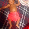 baby, child, infant, plaid_blanket, red_shorts, lying_down, folded_clothes, person, indoor, skin, bare_chest, footwear_absent, hand, face, head, blanket, fabric, pattern, relaxing, casual