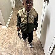 Khamari joined the competition — help win amazing prizes! child, boy, nike_jacket, lint_roller, hallway, wooden_floor, door, sneakers, clothing, indoor, curious, standing, young_child, casual, portrait, person, flooring, door_handle, expression, walking